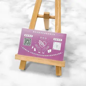 以淡紫底搭配反白圖文，印刷於萊妮紙上，紙張布紋在燈光下略顯立體。中央為品牌圖像，兩側有 QR Code 與插畫圖示，強化實用性質。