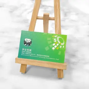 橫式綠色磨砂名片，印有公司名稱與標誌，右側設有幾何放射圖案。名片展現雙面細膩珍珠紋與局部光澤質感，呈現高雅而專業的磨砂效果。