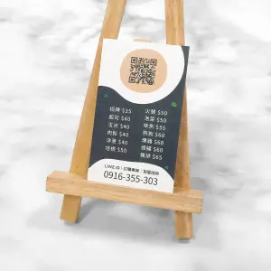 直式磨砂名片，白底搭配黑色與橘色設計，中央印有 QR Code，下方列出多項商品名稱與價格。名片表面呈現細緻的珍珠細紋與局部亮面效果，整體質感緊密、略帶細微粗糙感。