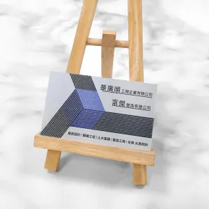 金綺紙名片，紙面具細緻皮革紋理與金屬光澤，搭配幾何線條構成藍灰相間的立體設計。表面光滑亮麗，呈現專業穩重的企業形象。