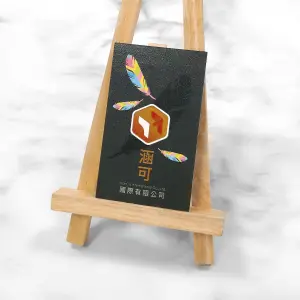 局部冷燙與彩色羽毛圖樣結合，黑底上閃耀金屬光澤，視覺立體鮮明，呈現品牌創意與精緻質感。