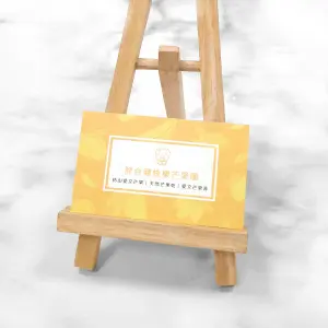 以明亮橘黃色為底的名片，印於萊妮紙上，布紋紋理在色塊間形成自然光影。圖樣融入芒果插畫，呈現果園品牌的陽光與溫度感。